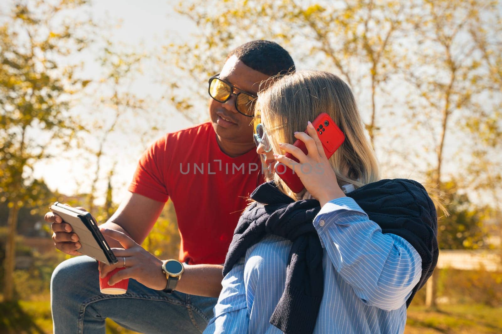 young man with sunglasses showing his friend a video on the digital tablet having fun an afternoon together in the park.