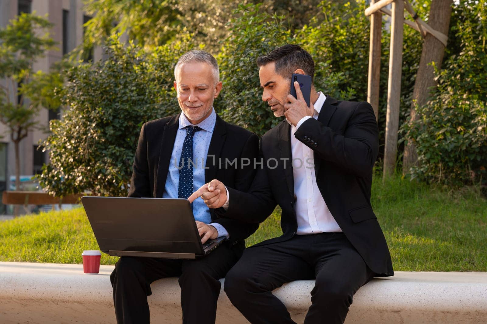 Two trusted business colleagues dressed in formal attire with a computer in hand observing the results of the work done