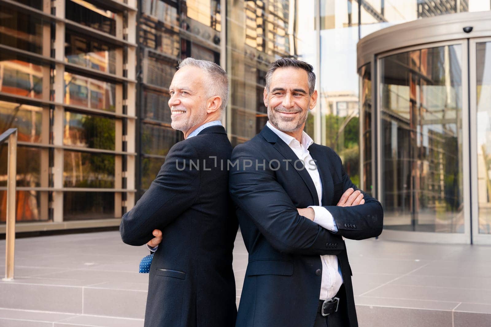 Two colleagues face each other, look smiling at the camera, work as a team, ready to start a new project, pose outdoors