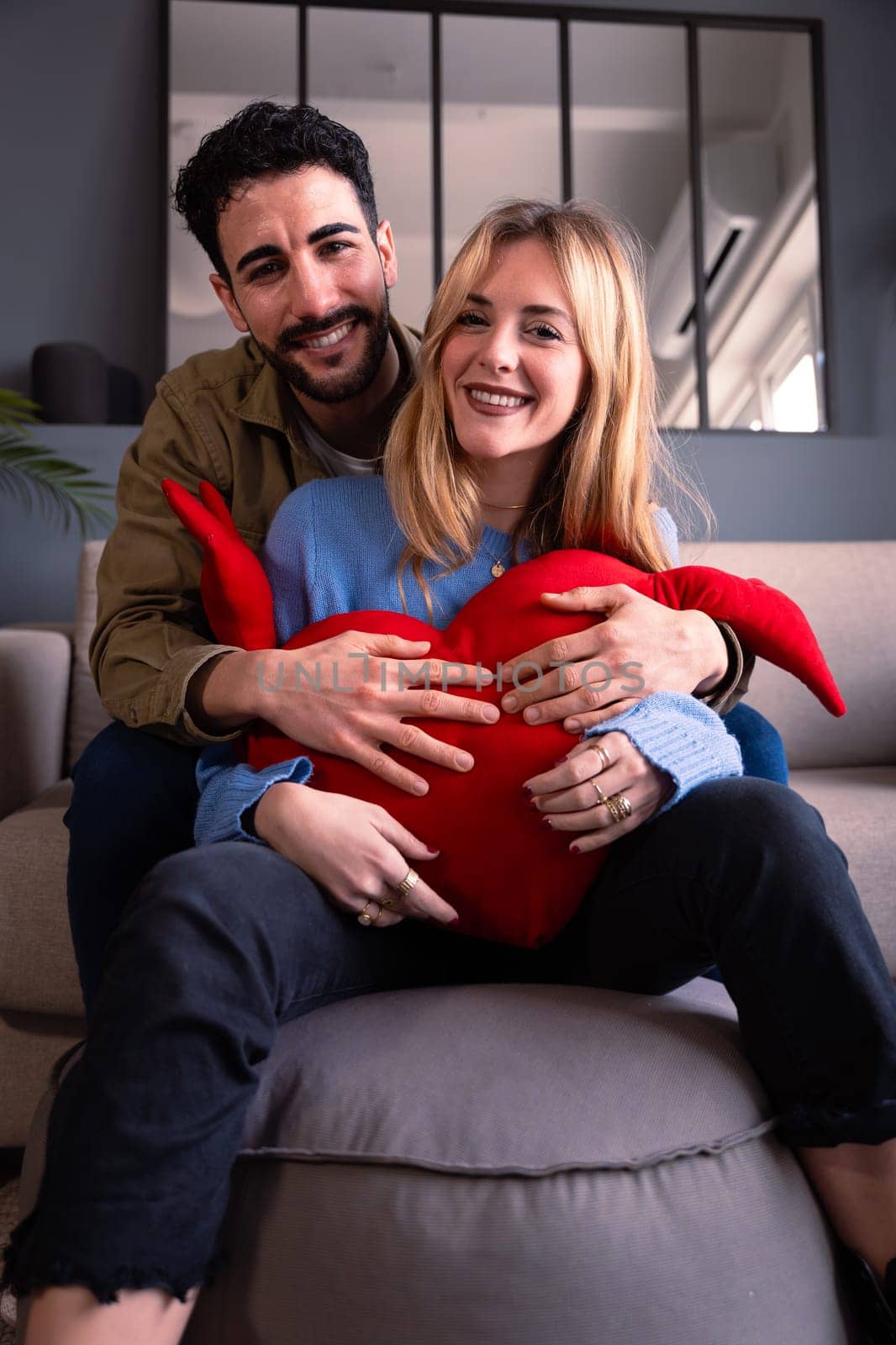Young couple smiling with a giant heart looking At camera. Valentine's Day.