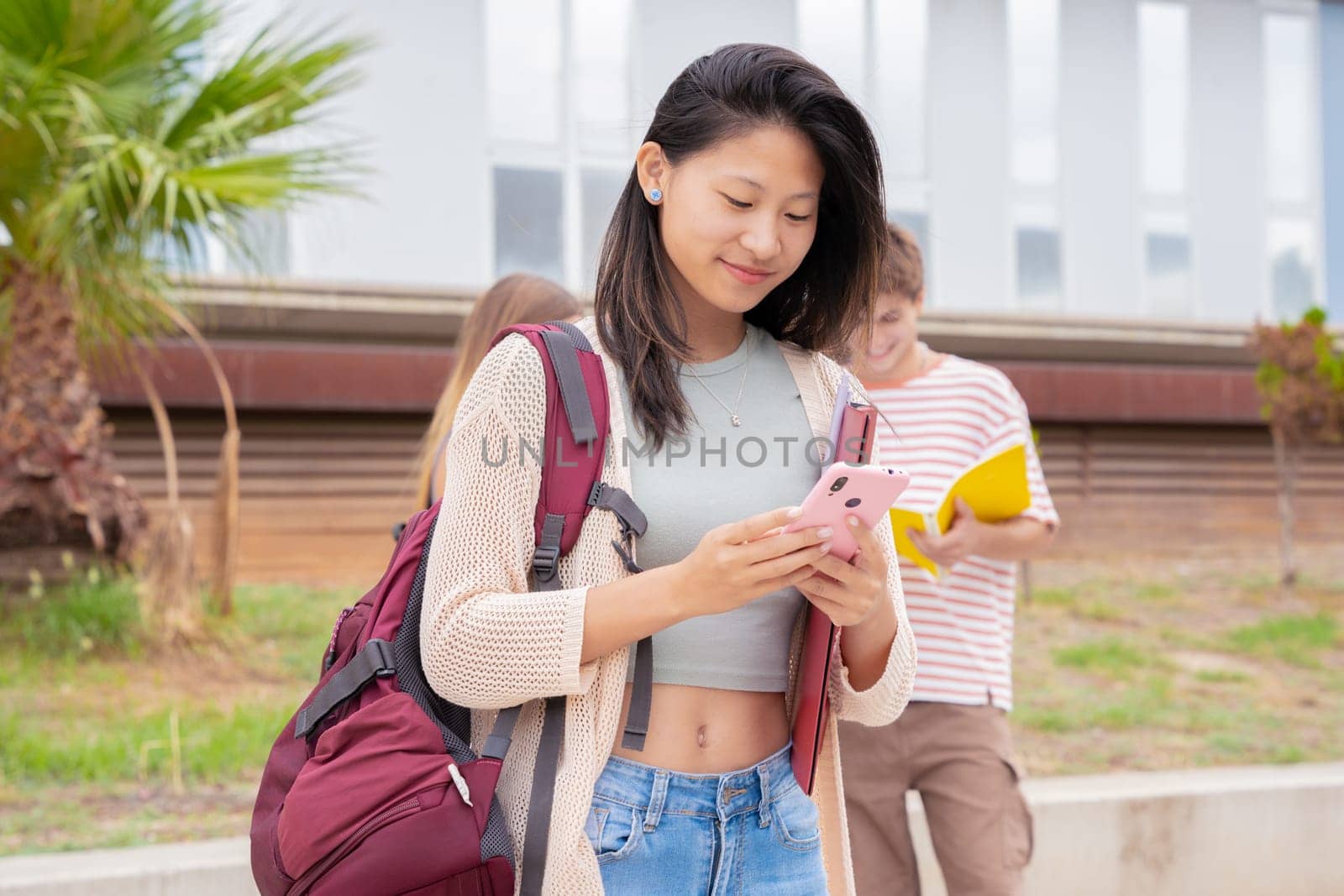 Asian student using social media with smartphone app and wireless technology outdoors