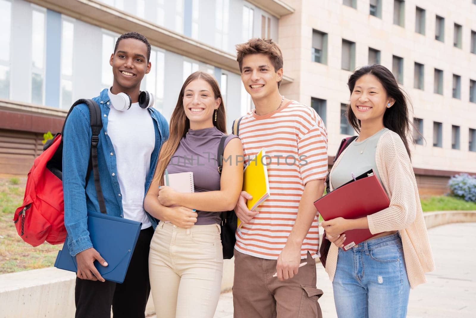 Happy group of college friends with notebooks in hand laughing making a selfie on campus. university life concept