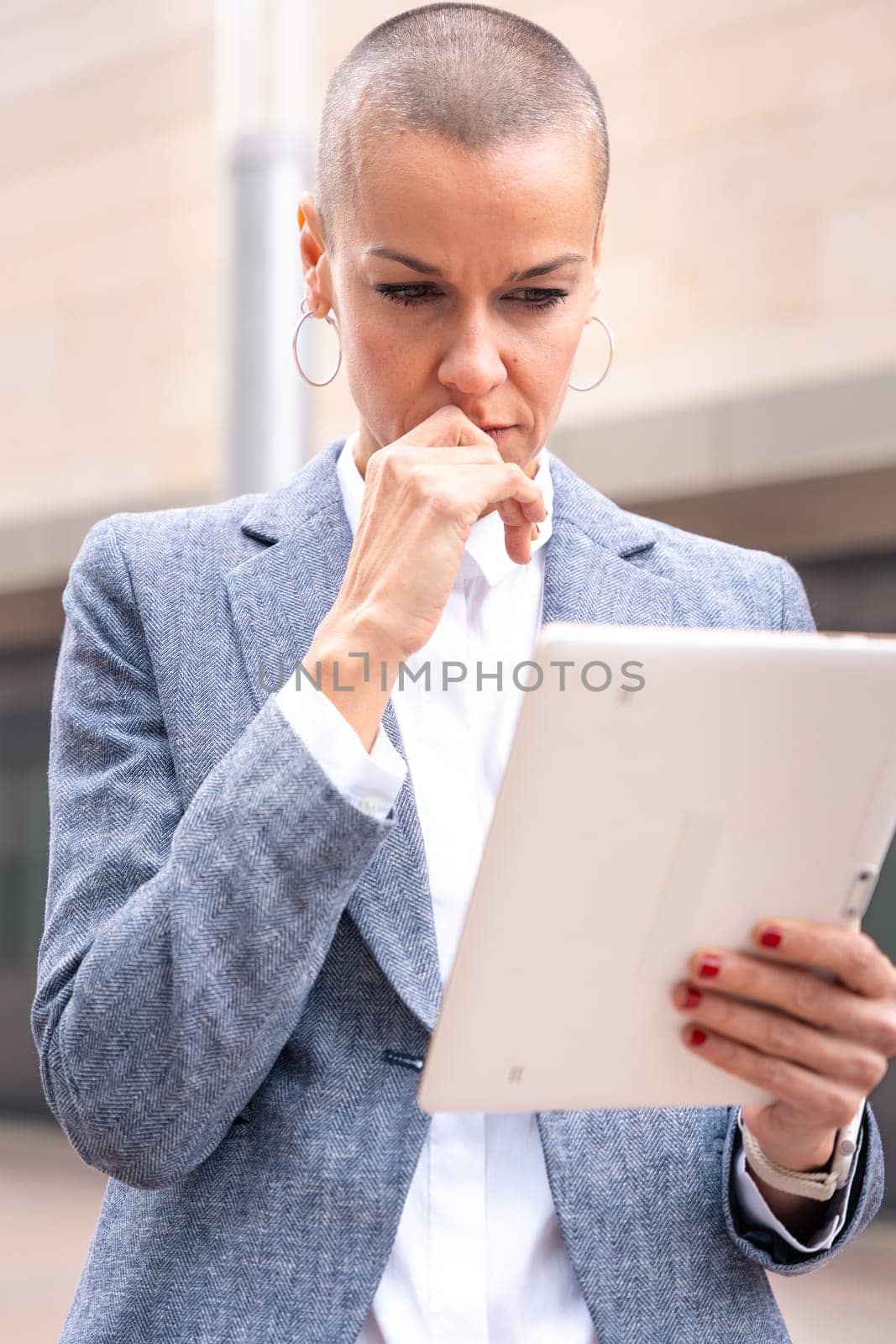 Thoughtful businesswoman with results of businesswoman walking down the street outside office building, a mature boss holds a phone in her hands, writes messages and reads news online, using an app.
