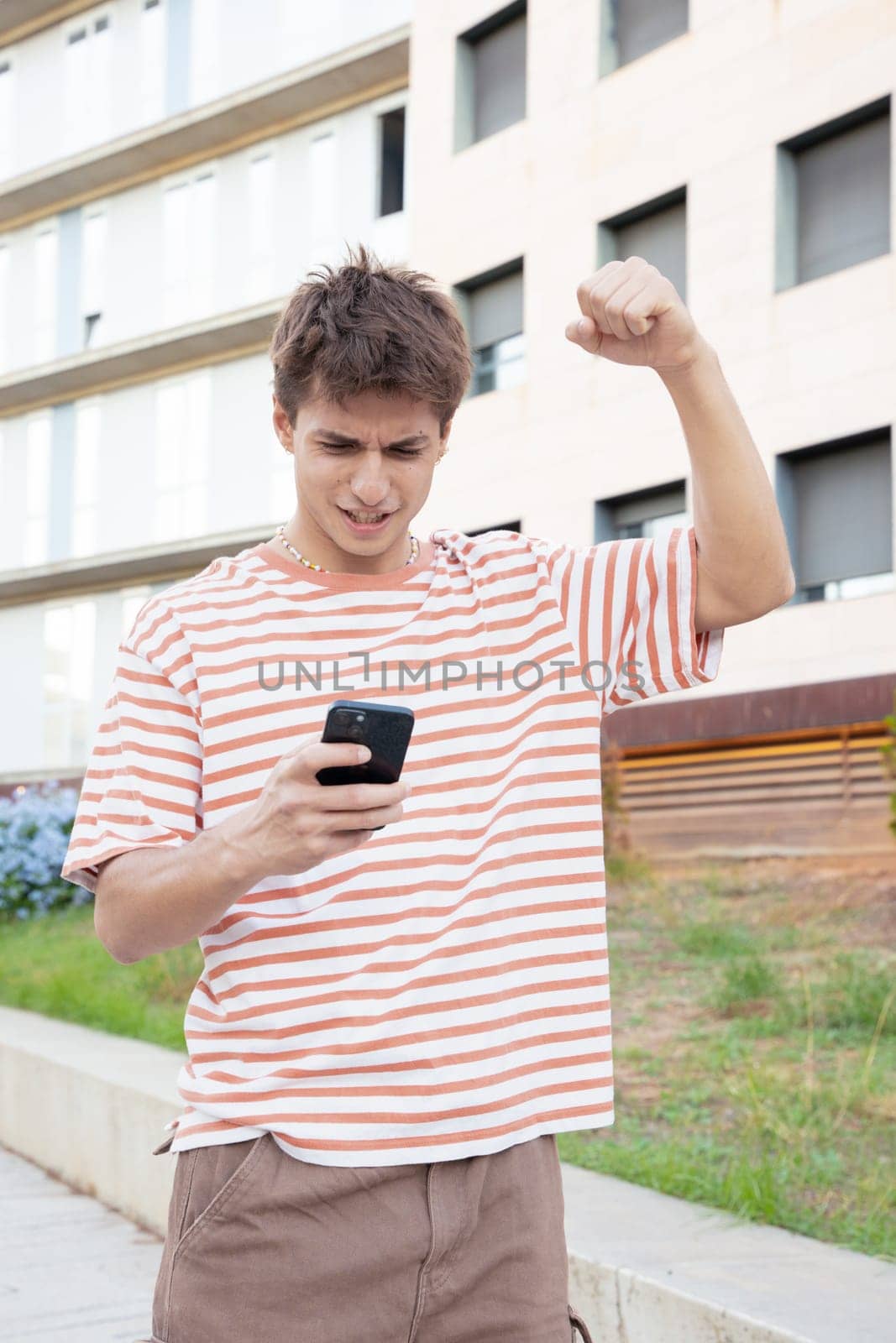 Excited caucasian man using mobile phone watching football match. Student euphoric about the exam result.