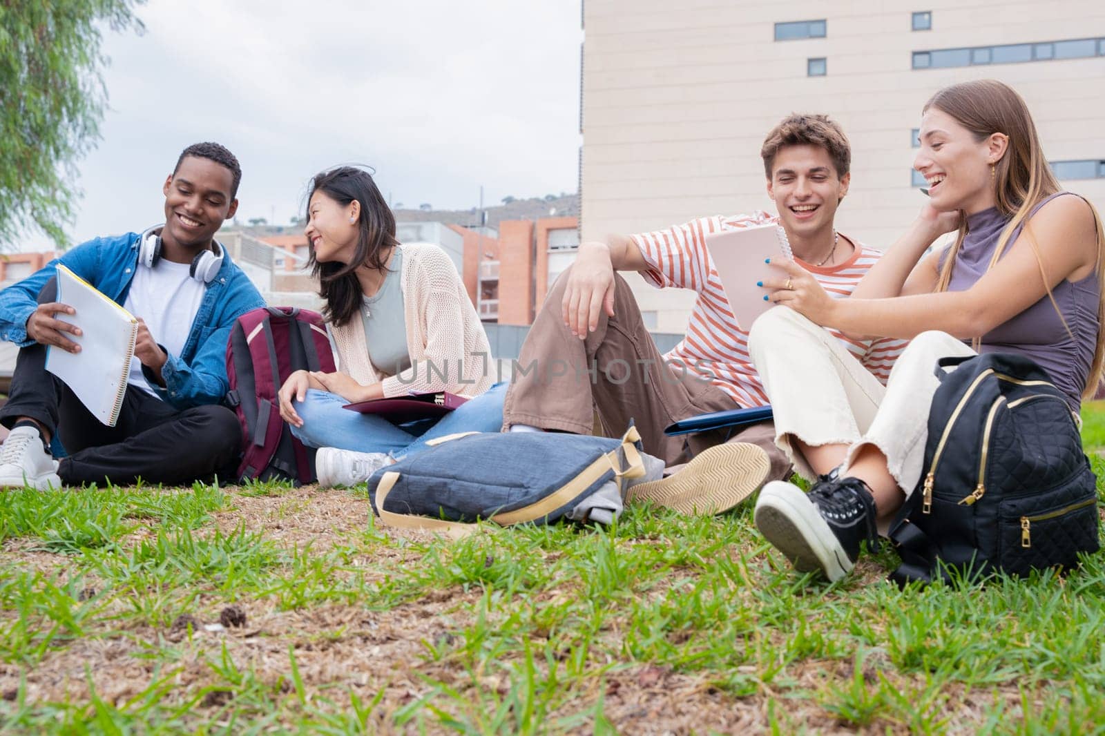 Diverse multiethnic friends relaxing after class outdoors. University life concept