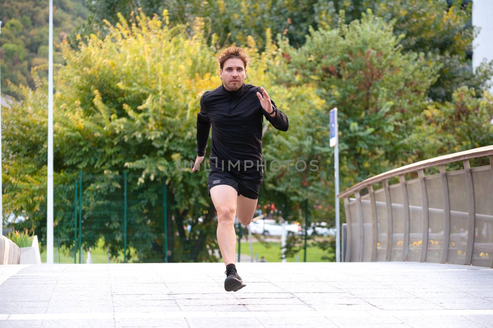 Young caucasian athlete with headphones training outdoors.