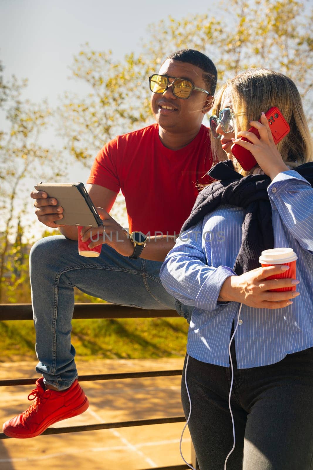 young man with sunglasses showing his friend a video on the digital tablet having fun an afternoon together in the park.