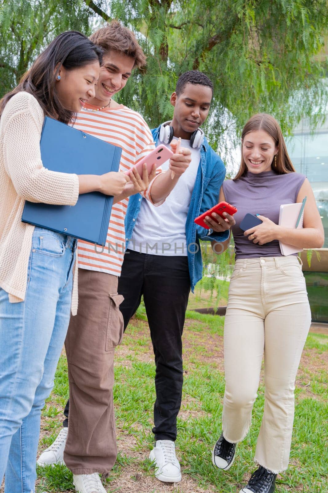 Group of friends using looking at their smartphones Multiracial teenagers browsing the internet with mobile phone on campus