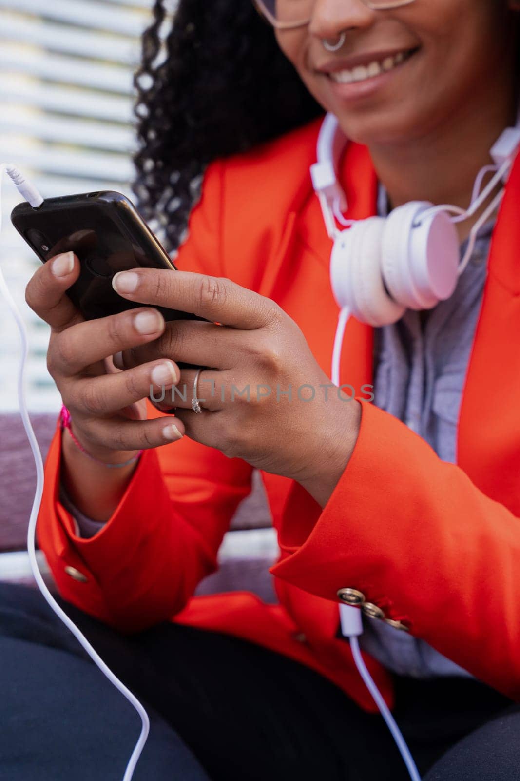 Vertical shot Beautiful black woman smiling using a social media app on a mobile phone outdoors. Girl chatting on mobile phone