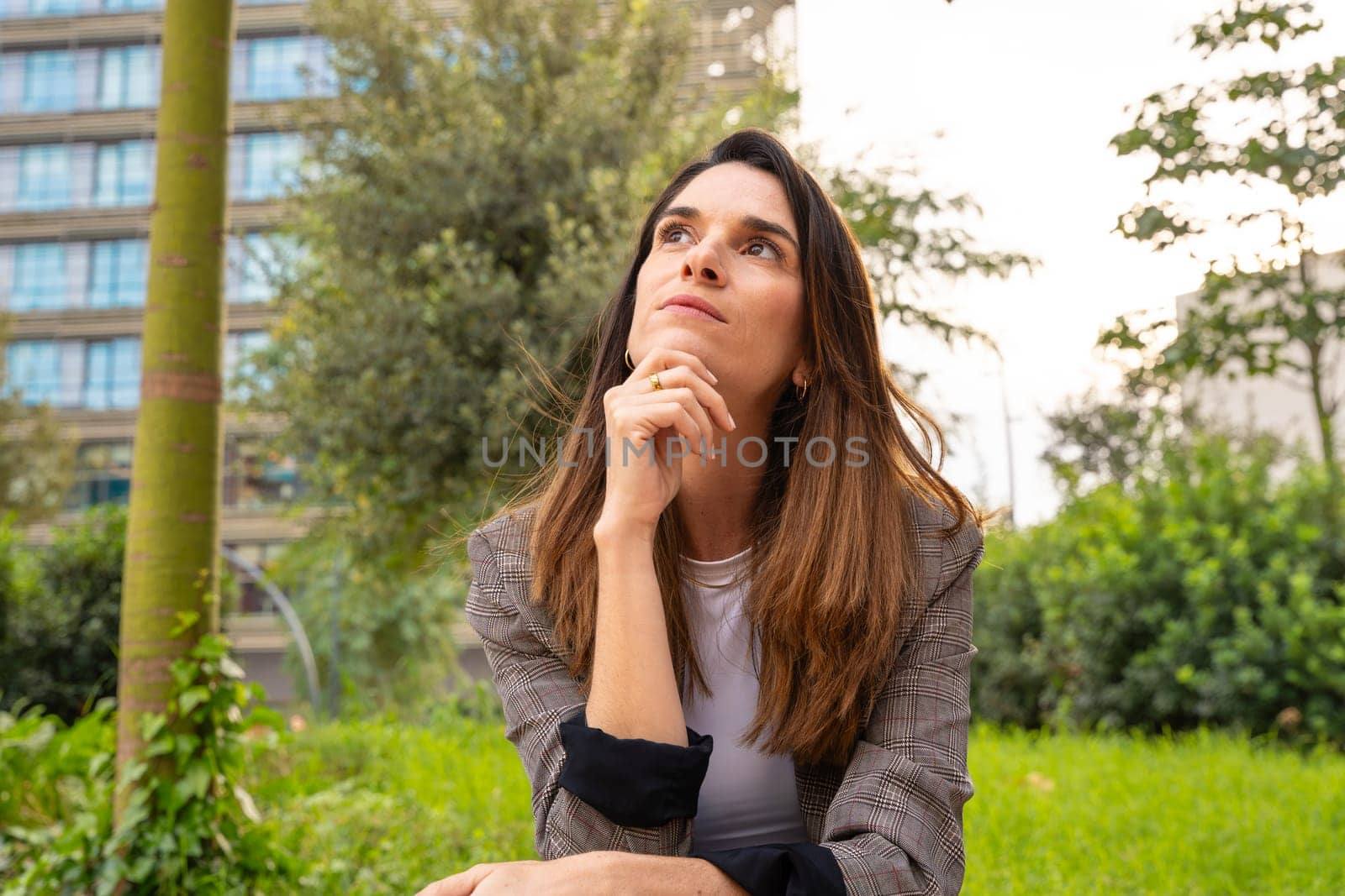 Thoughtful business woman with business woman results sitting on the street outside the office building, a mature boss staring into infinity with thoughtful face.