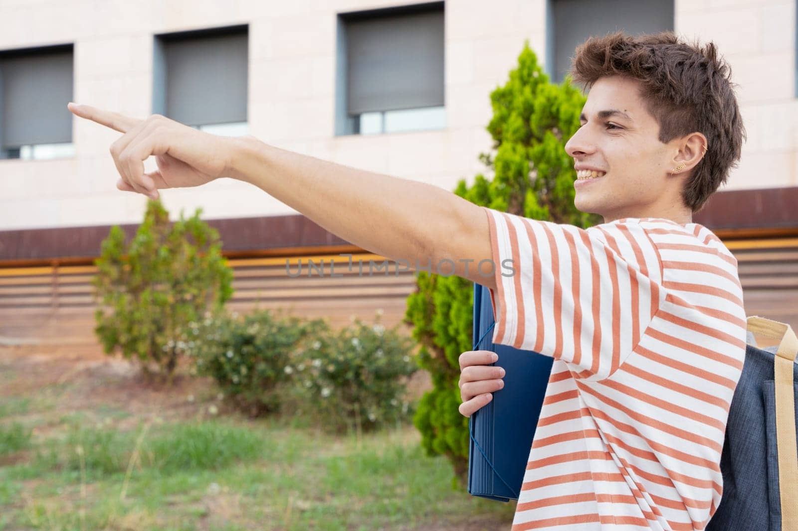 Caucasian teenage student pointing finger to the side of the logo. Man showing signs