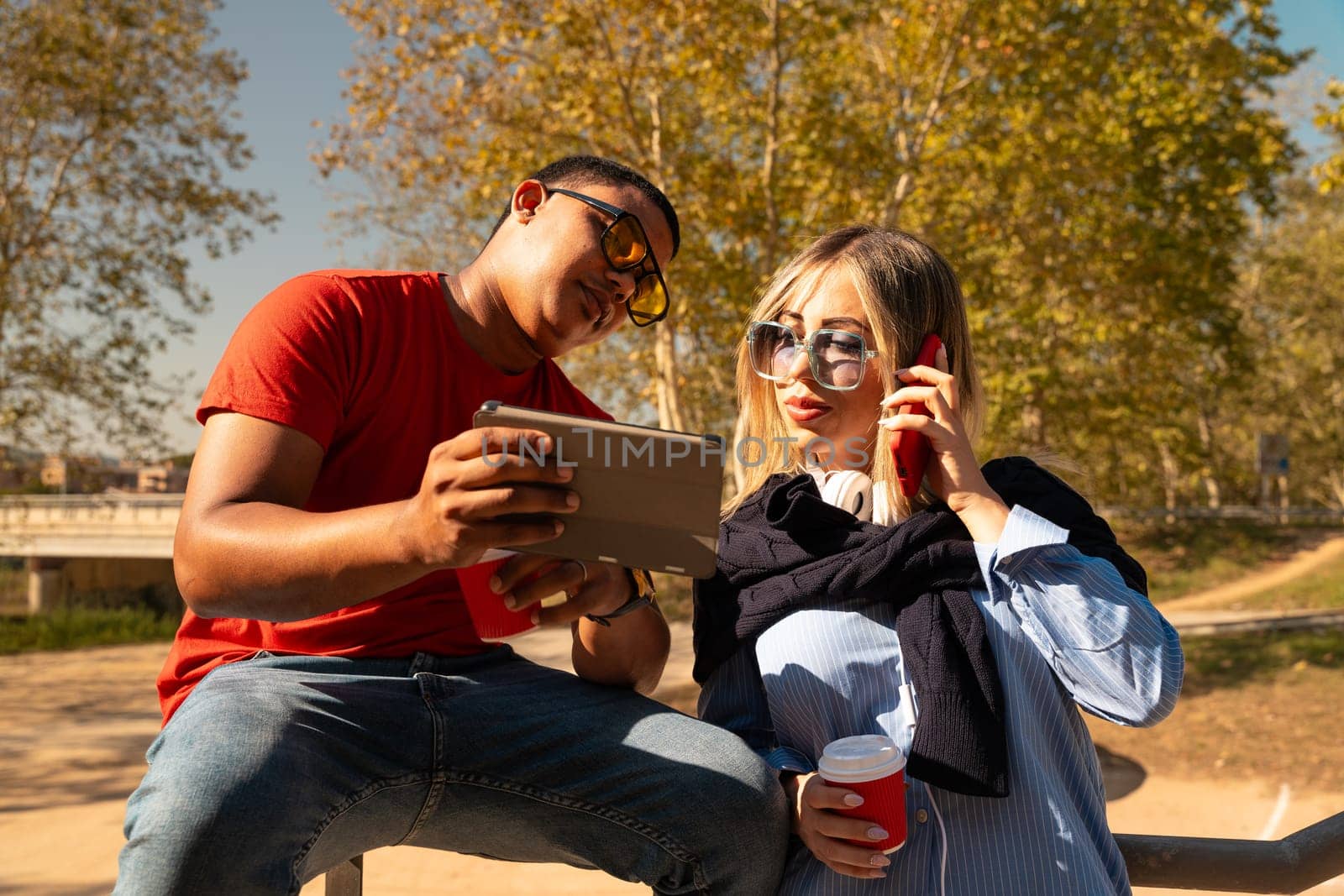 young man with sunglasses showing his friend a video on the digital tablet having fun an afternoon together in the park.