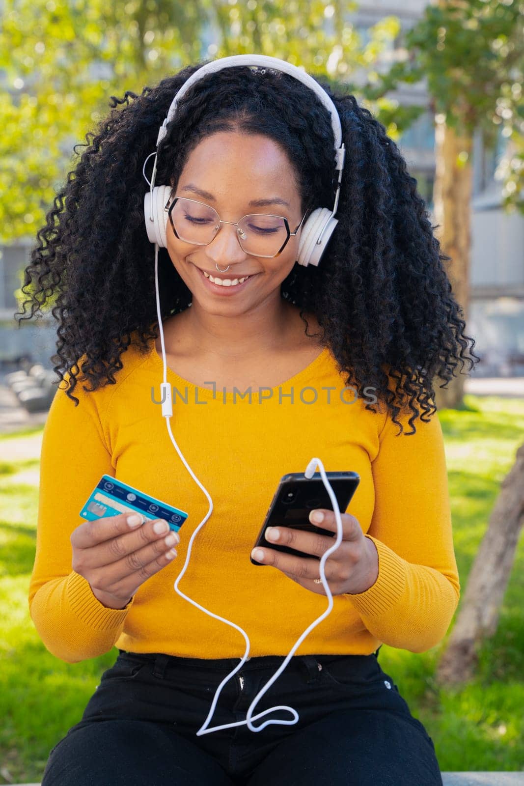 vertical photo happy black woman with credit card and smartphone in hands. Concept: online shopping