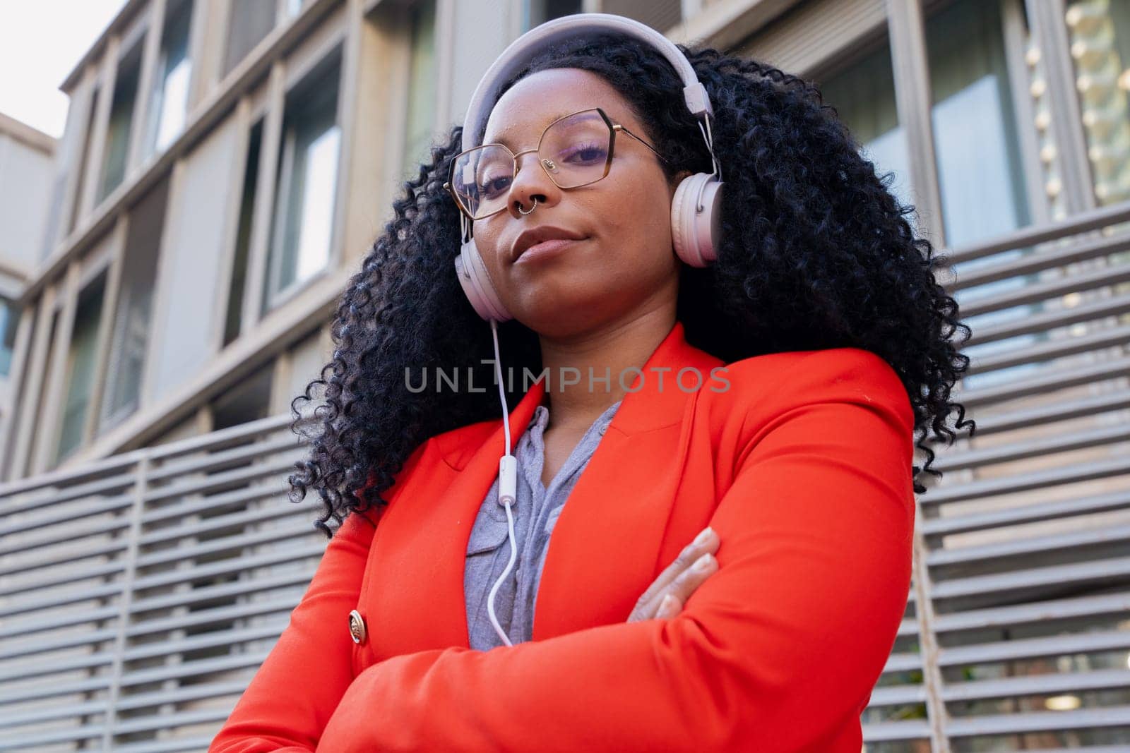 Thoughtful young woman with headphones looking at camera. Front view of a black woman with afro hair. Head shot of a proud businesswoman