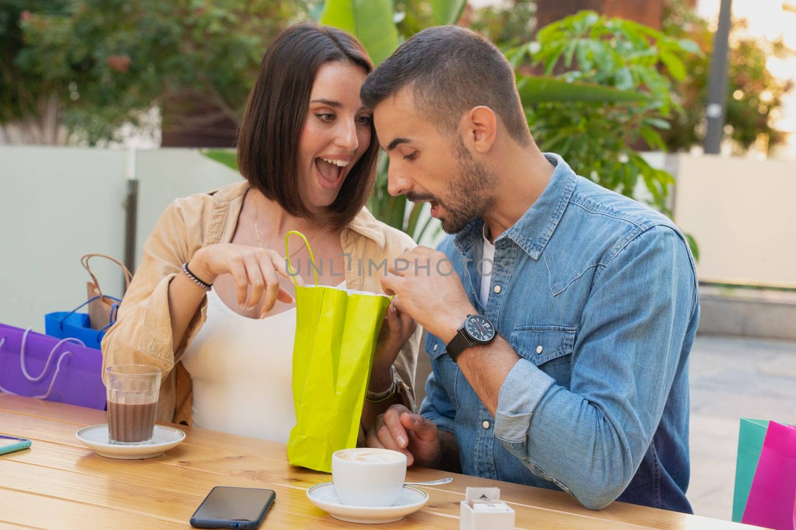 sale, shopping, consumerism, leisure and people concept - happy couple with shopping bags drinking coffee at shopping center