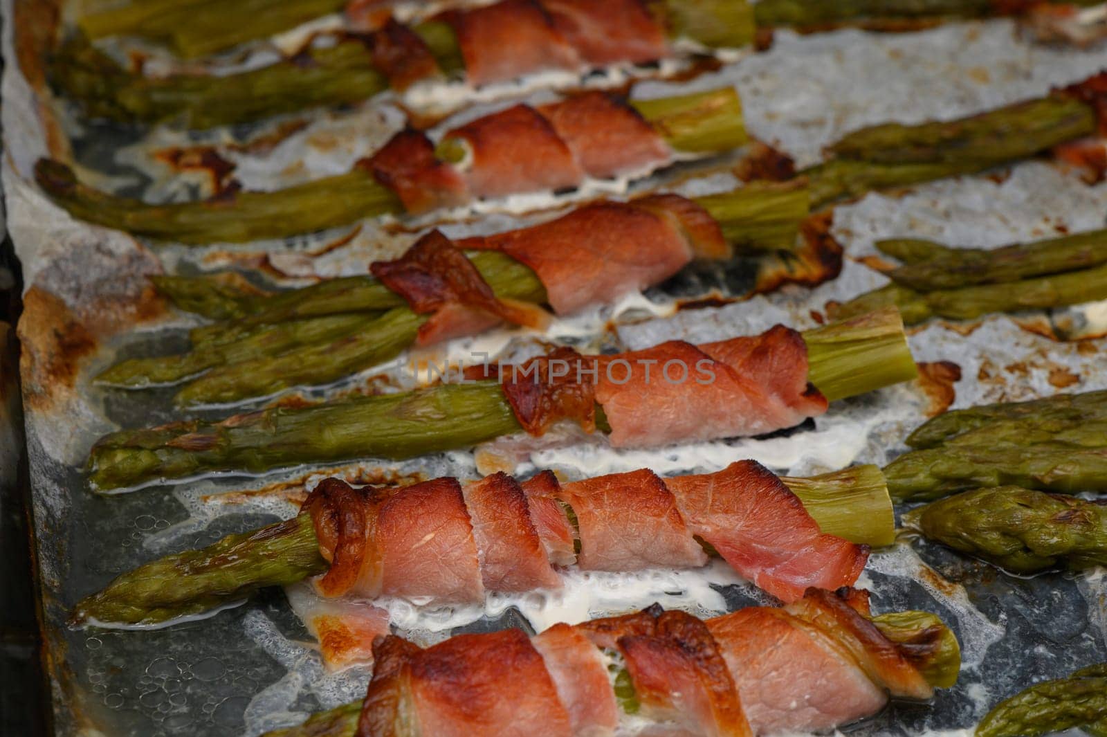 Delicious asparagus wrapped in bacon sizzles on a grill, capturing a warm afternoon's culinary delight outdoors.