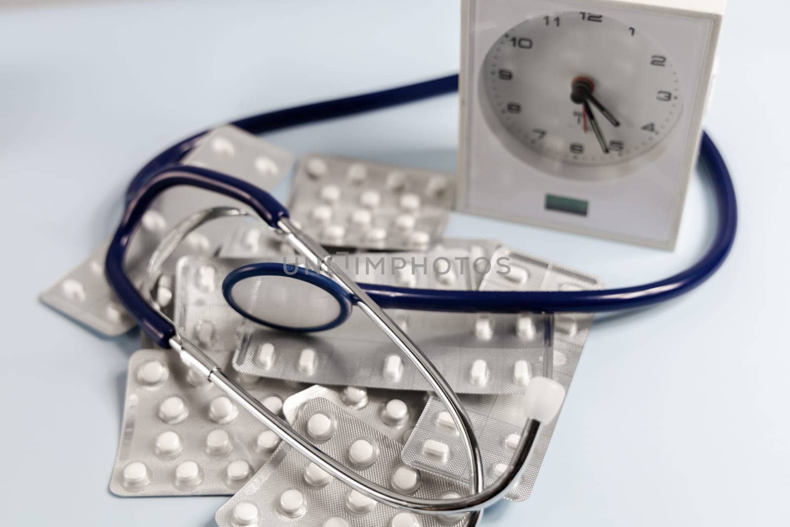 A bunch of pills in blister and a table clock. Concept of taking pills on time. High quality photo