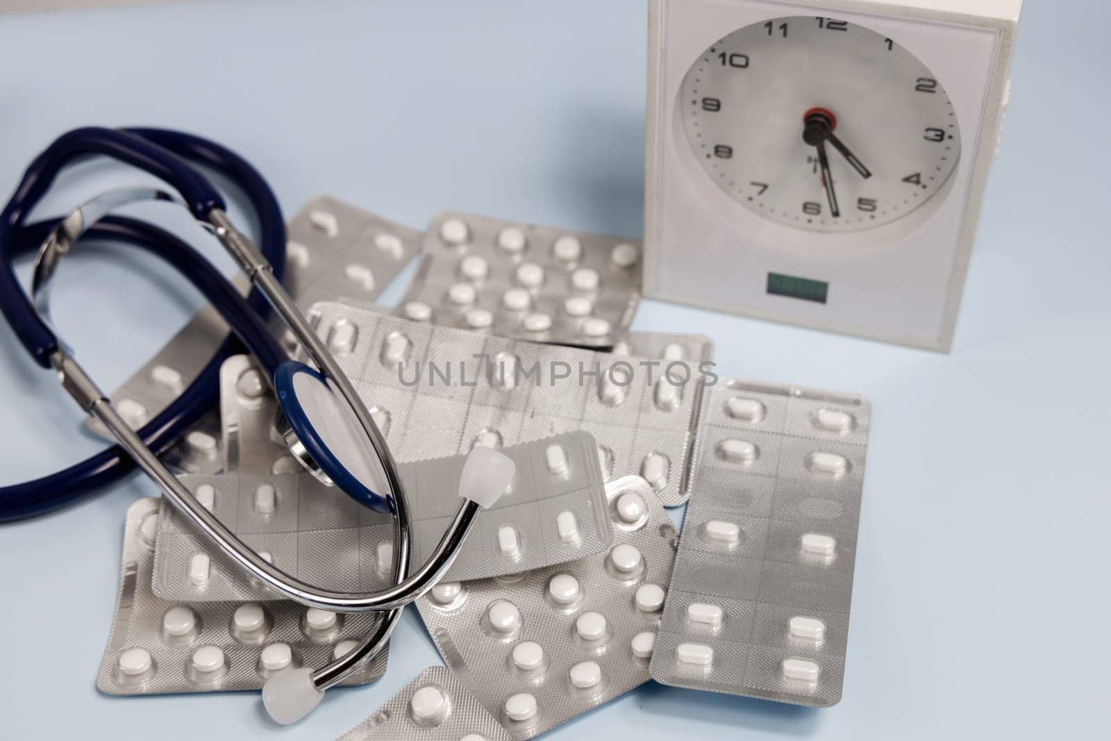 A bunch of pills in blister and a table clock. Concept of taking pills on time. High quality photo