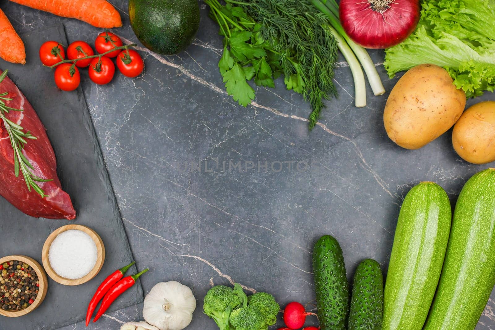 The concept of diet, proper and healthy nutrition, recipes. Top view of raw beef steak with a sprig of rosemary lying on a black stone plank surrounded by vegetables, herbs, spices on a dark background with space for text in the center. High quality photo