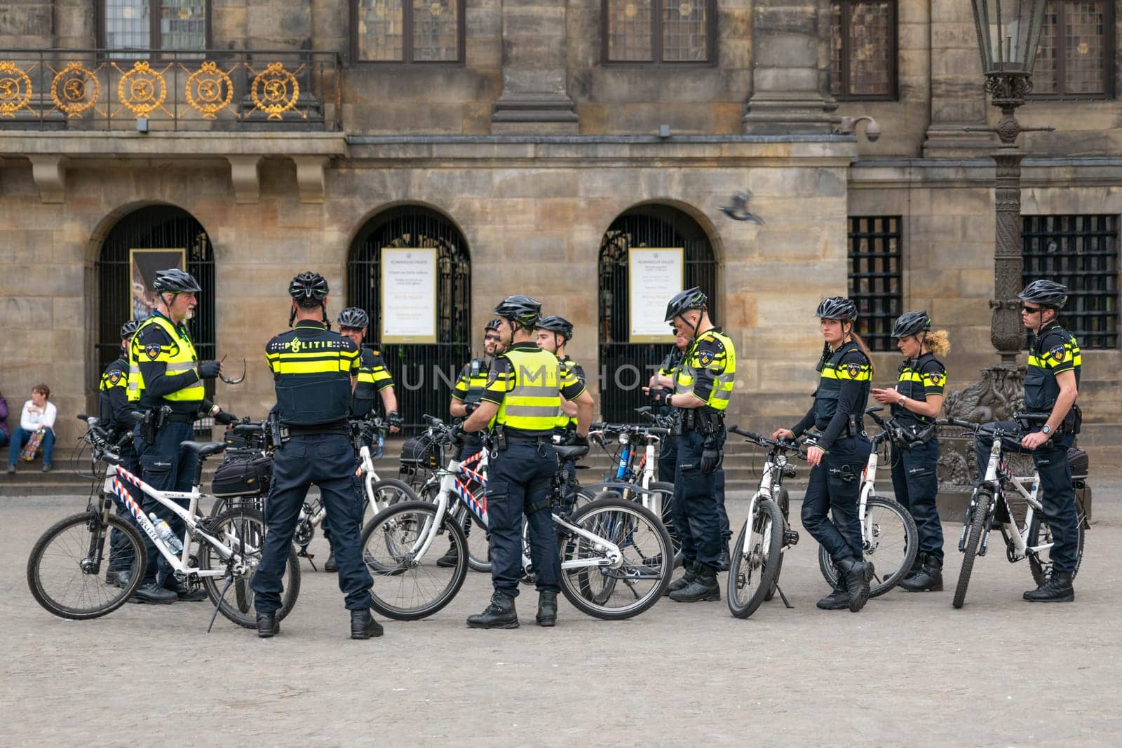 AMSTERDAM, THE NETHERLANDS - APRIL 16, 2019: Uniformed police officers on bicycles wearing helmets maintain order. Surveillance in the center of the city.