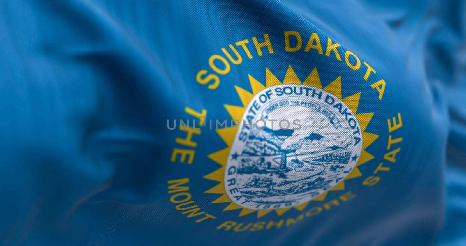Close-up of the South Dakota flag waving in the wind. Sky blue field, the state seal, and inscriptions of South Dakota and The mount rushmore state. 3d illustration render. Selective focus