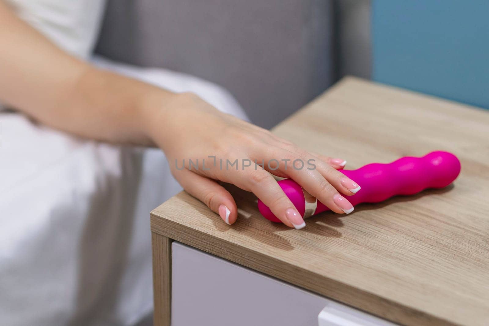 Young woman holding sex toy dildo vibrator in bed.