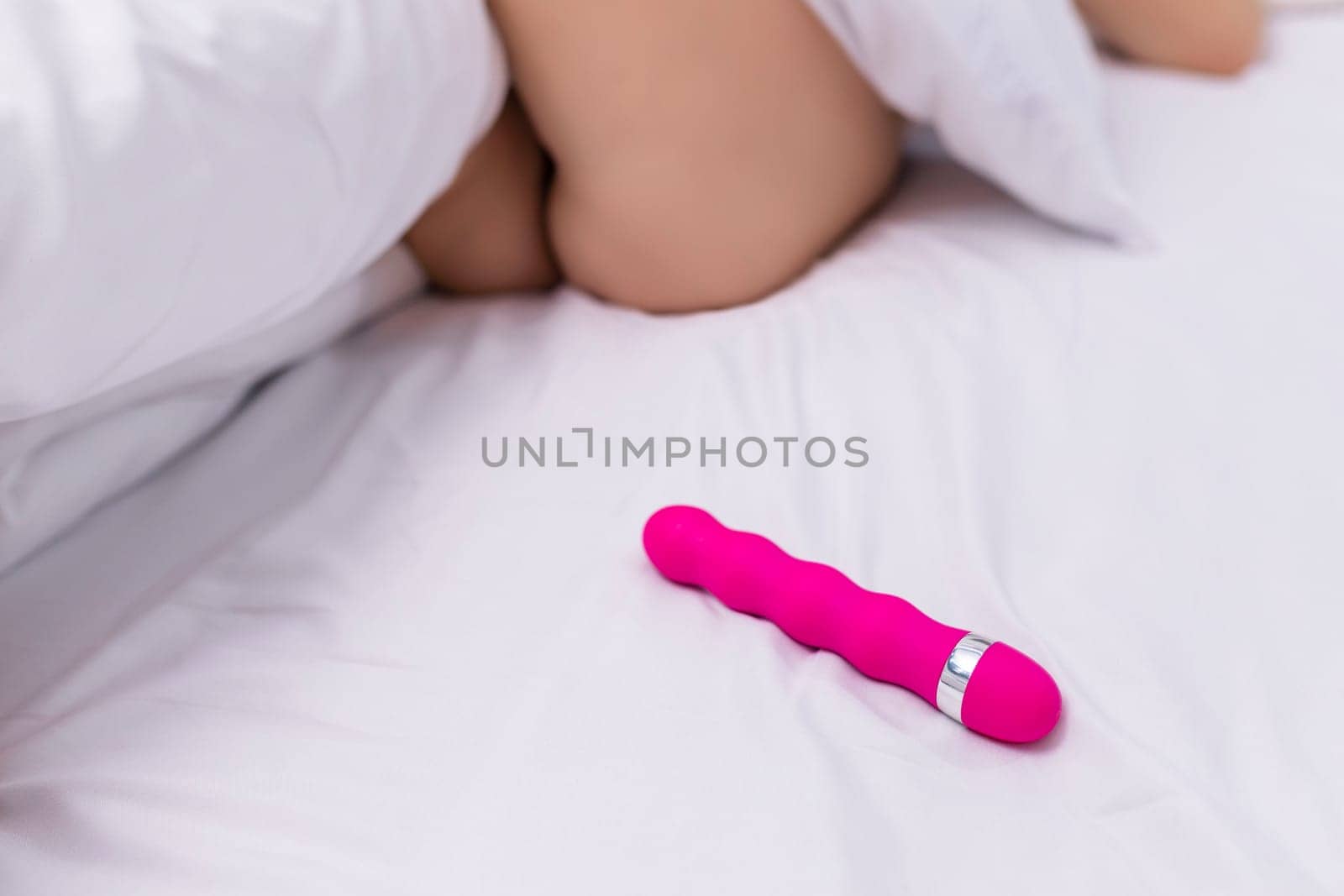 Young woman holding sex toy dildo vibrator in bed.