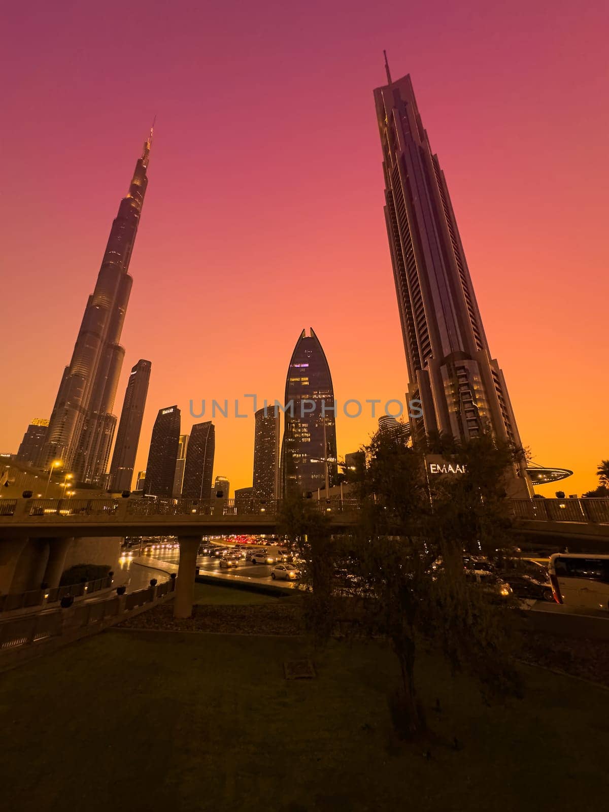 UAE, Dubai, 19 December 2024: The famous Burj Khalifa skyscraper at dusk, Dubai's sights during the incredible sunset sky, skyscrapers illuminated at night, pink sky, palm trees. High quality photo