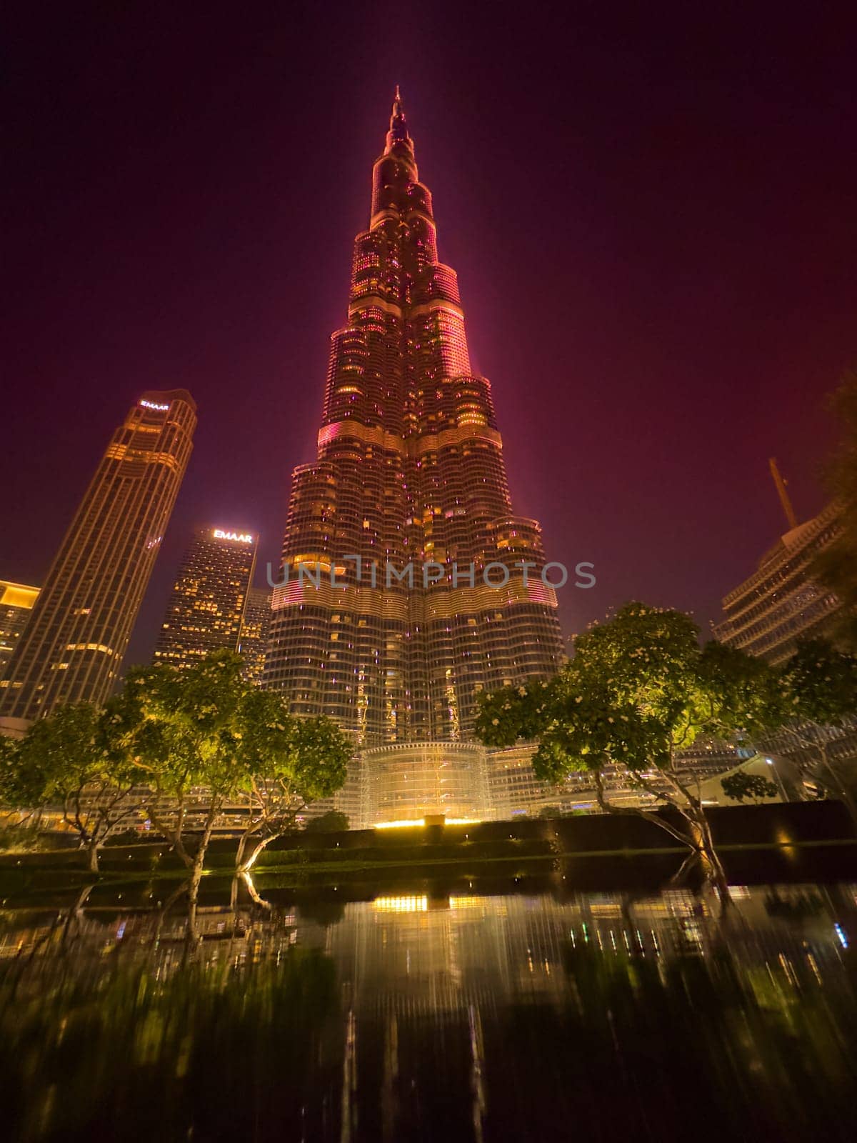 UAE, Dubai, 25 November 2024: The famous Burj Khalifa skyscraper at dusk, Dubai's sights during the incredible sunset sky, skyscrapers illuminated at night, pink sky, palm trees. High quality photo