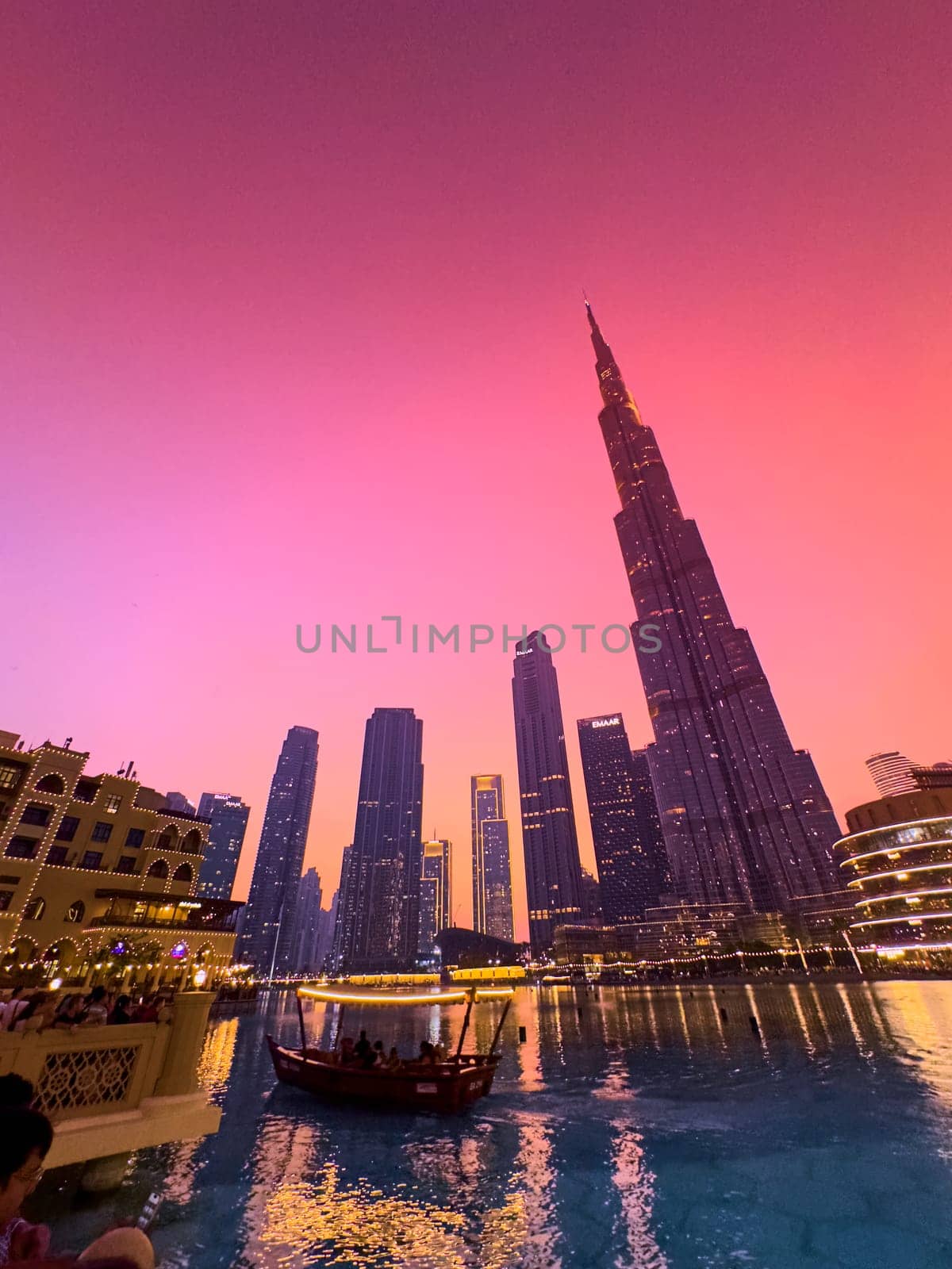 UAE, Dubai, 26 December 2024: The famous Burj Khalifa skyscraper at dusk, Dubai's sights during the incredible sunset sky, skyscrapers illuminated at night, pink sky, palm trees. High quality photo