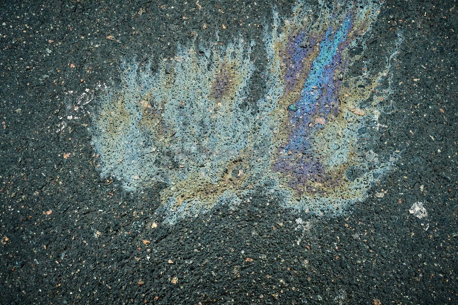 Oil spill creating a unique stain on the asphalt, offering an abstract representation of gasoline and motor oil.