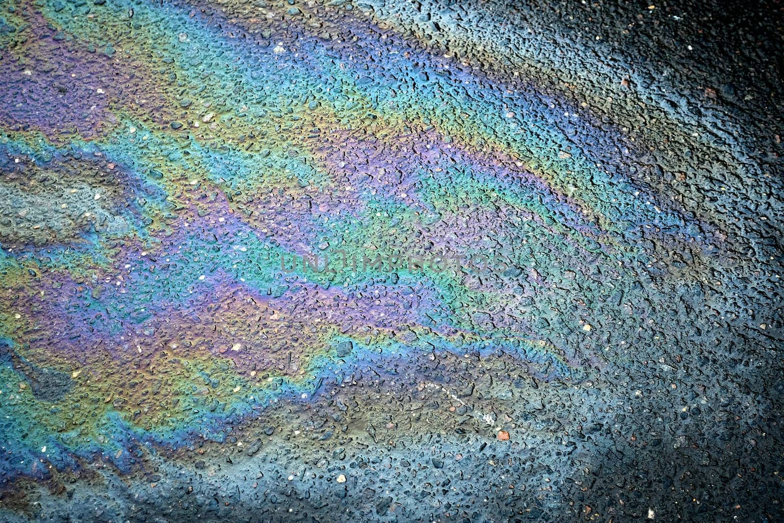 Motor oil stain on the pavement producing an intriguing abstract background of spilled fuel