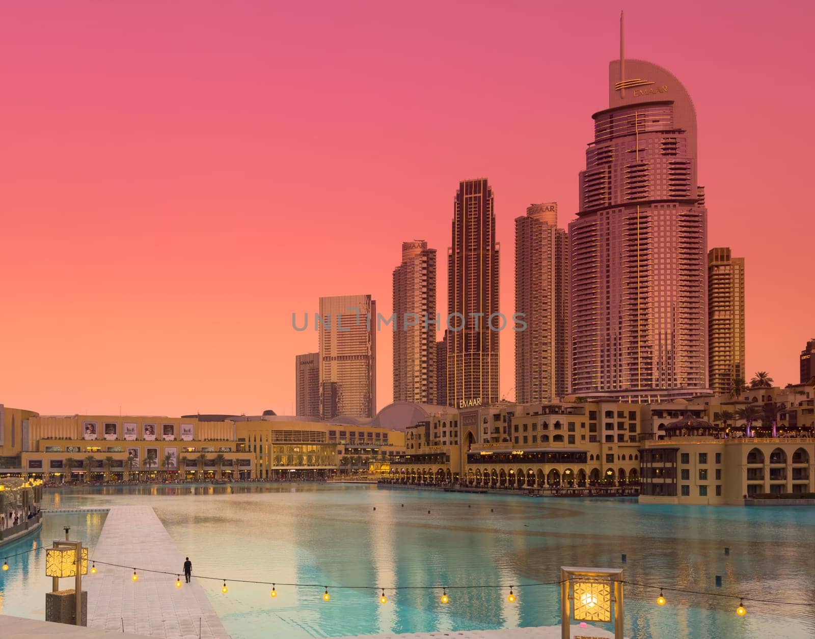 UAE, Dubai, 11 December 2024: The famous Burj Khalifa skyscraper at dusk, Dubai's sights during the incredible sunset sky, skyscrapers illuminated at night, pink sky, palm trees. High quality photo