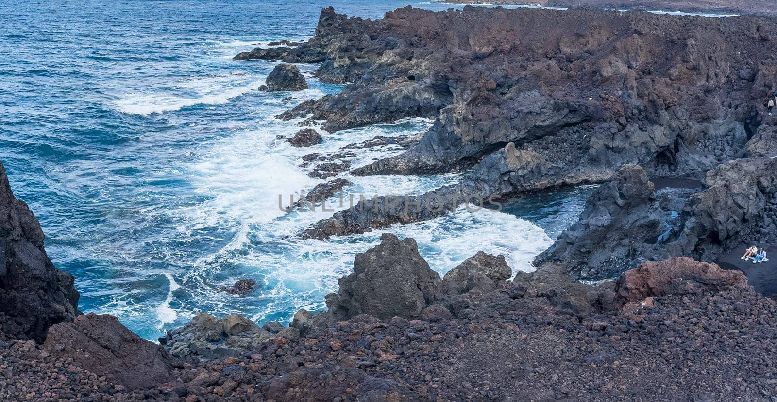 A breathtaking view of a rugged volcanic coastline, featuring waves crashing against rocks, showcasing the beauty of natural seaside landscapes.