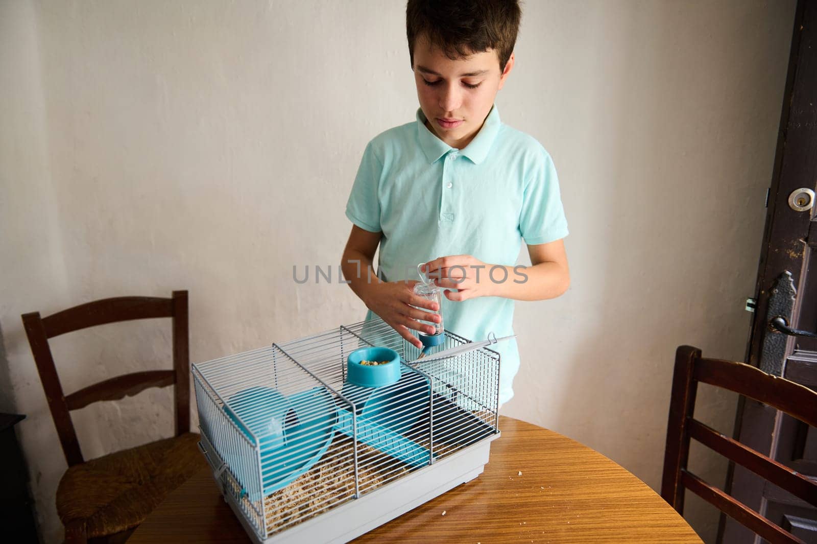 Young boy feeding or taking care of a pet in a cage, displaying affection and responsibility for animals.
