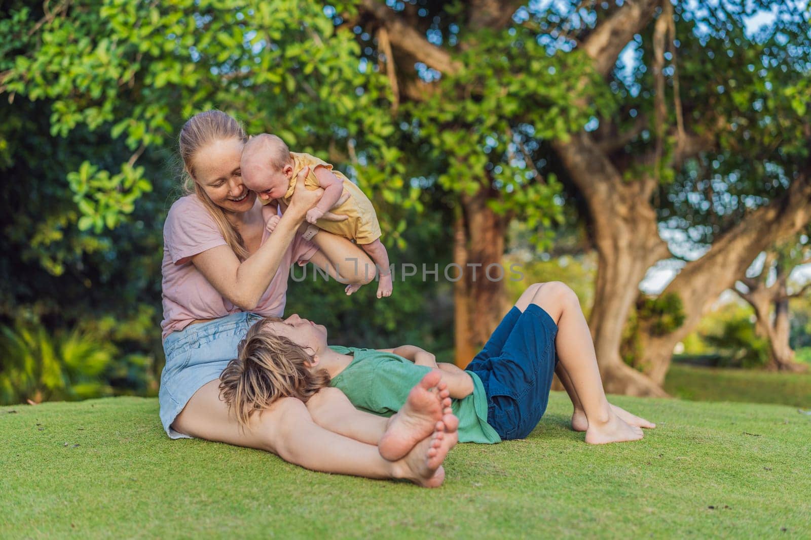 Young mother, teenage son, and one-month-old baby enjoying quality family time in the park. Multigenerational bonding and outdoor family love concept.
