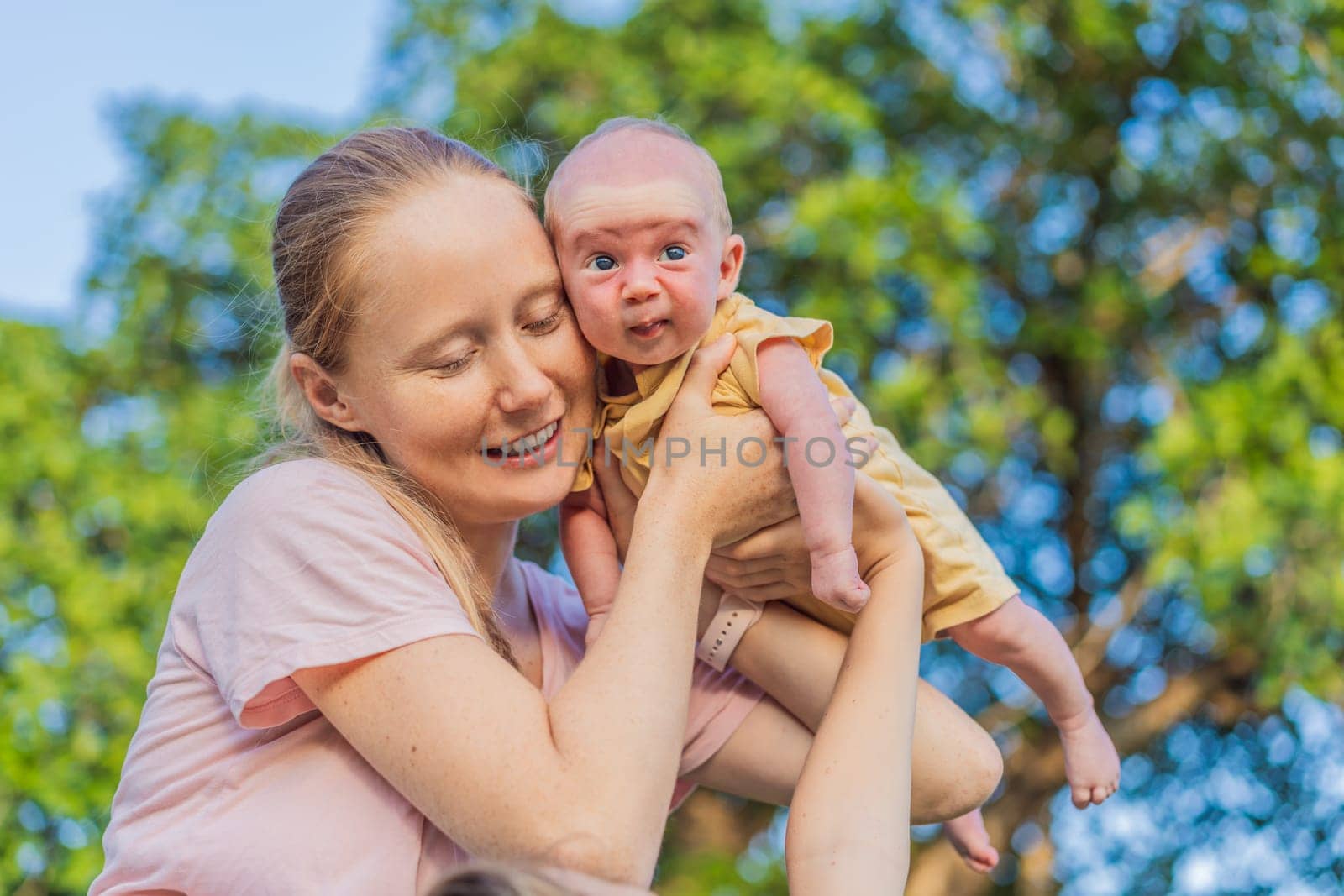 Young mother, teenage son, and one-month-old baby enjoying quality family time in the park. Multigenerational bonding and outdoor family love concept.
