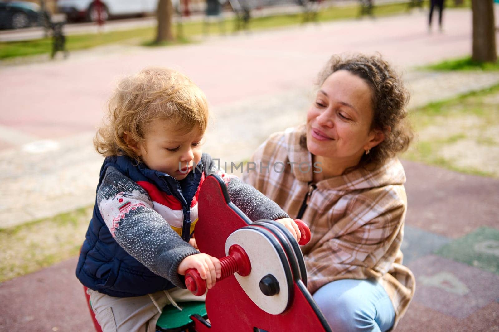 A warm moment of a mother and her child enjoying playful activities on a sunny day outdoors.