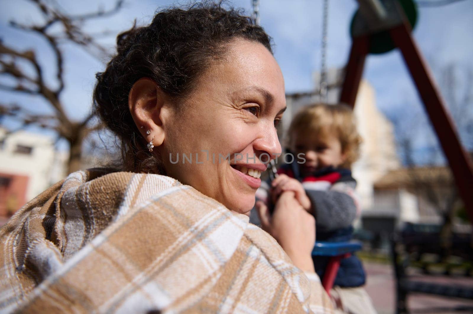 A happy mother shares a joyful moment outdoors with her young child at the playground, capturing warmth and bonding.