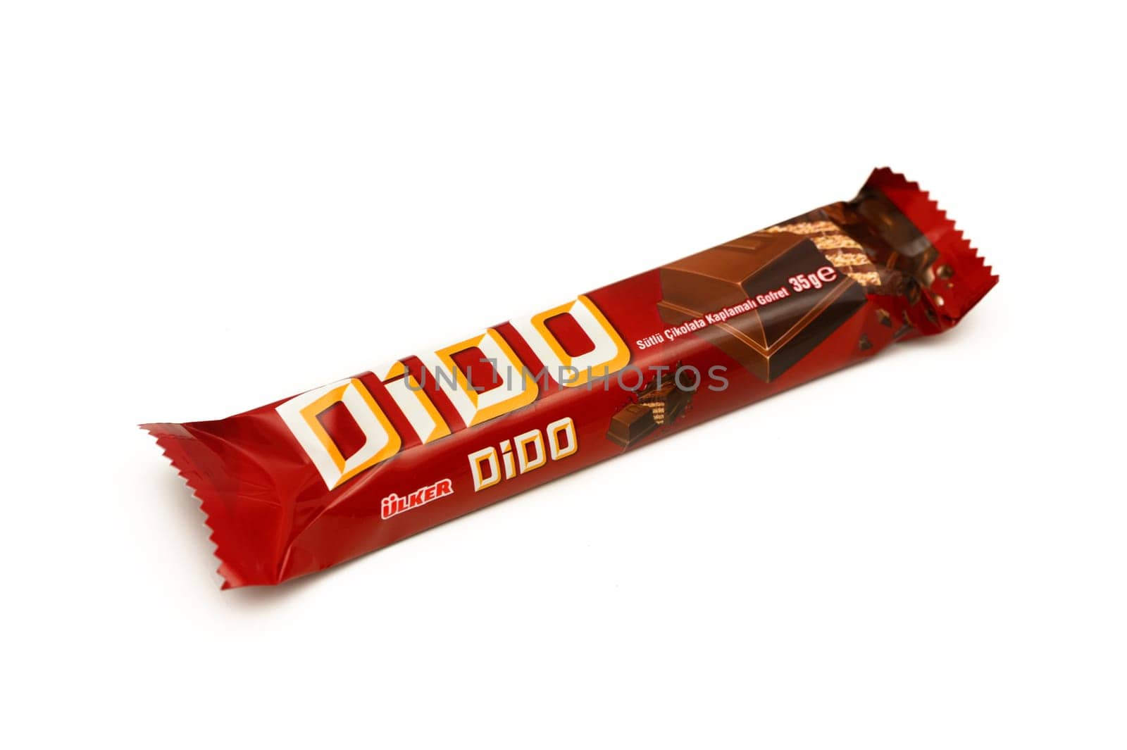 Gaziveren Cyprus -10.02.2025 A tempting chocolate bar wrapped in a bright red package sits appealingly on a white surface, waiting to be tasted.