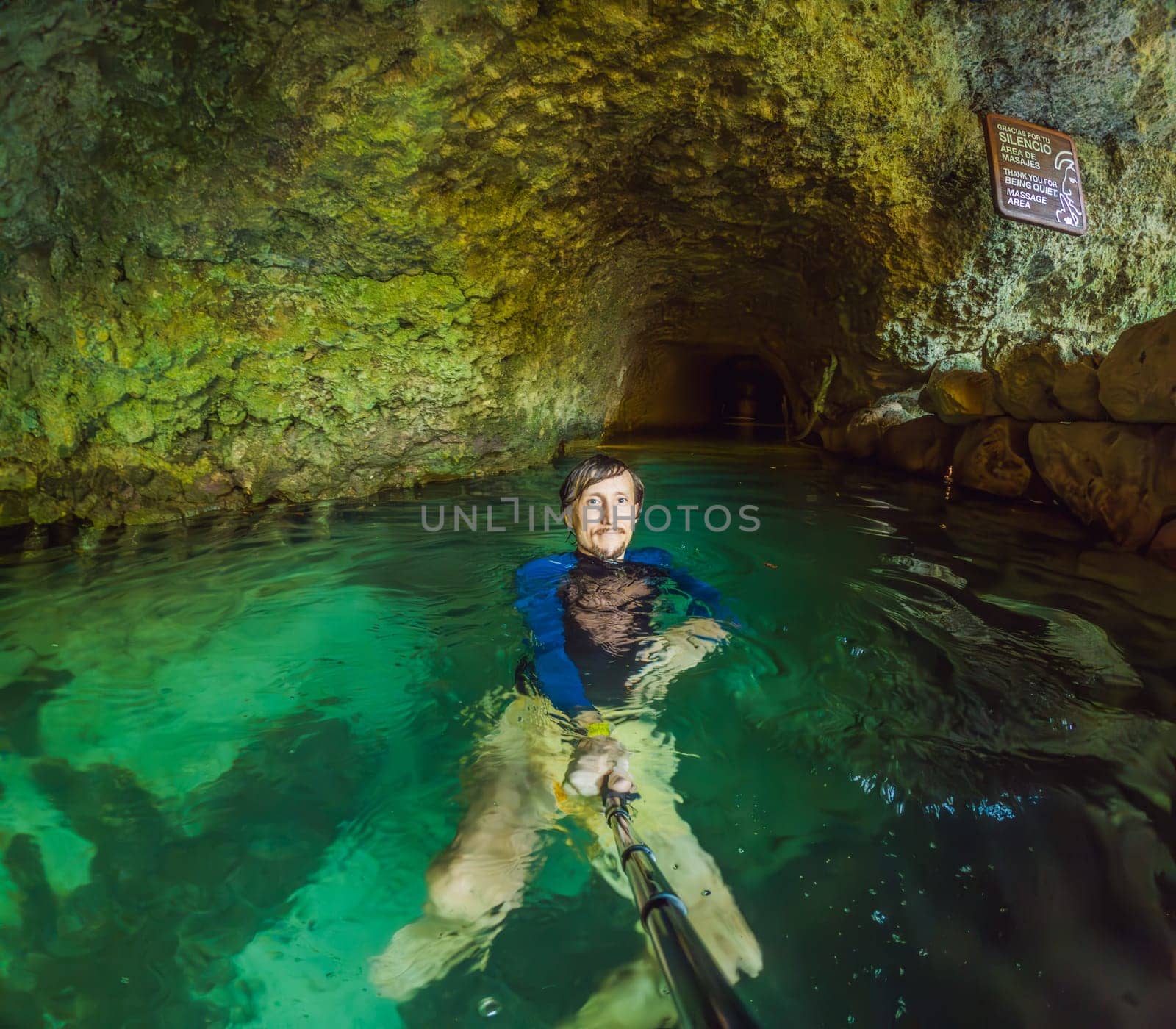 Man tourist in the water of a Mexican cenote surrounded by natural beauty. Adventure travel, eco-tourism, and exploration concept in a tropical paradise.