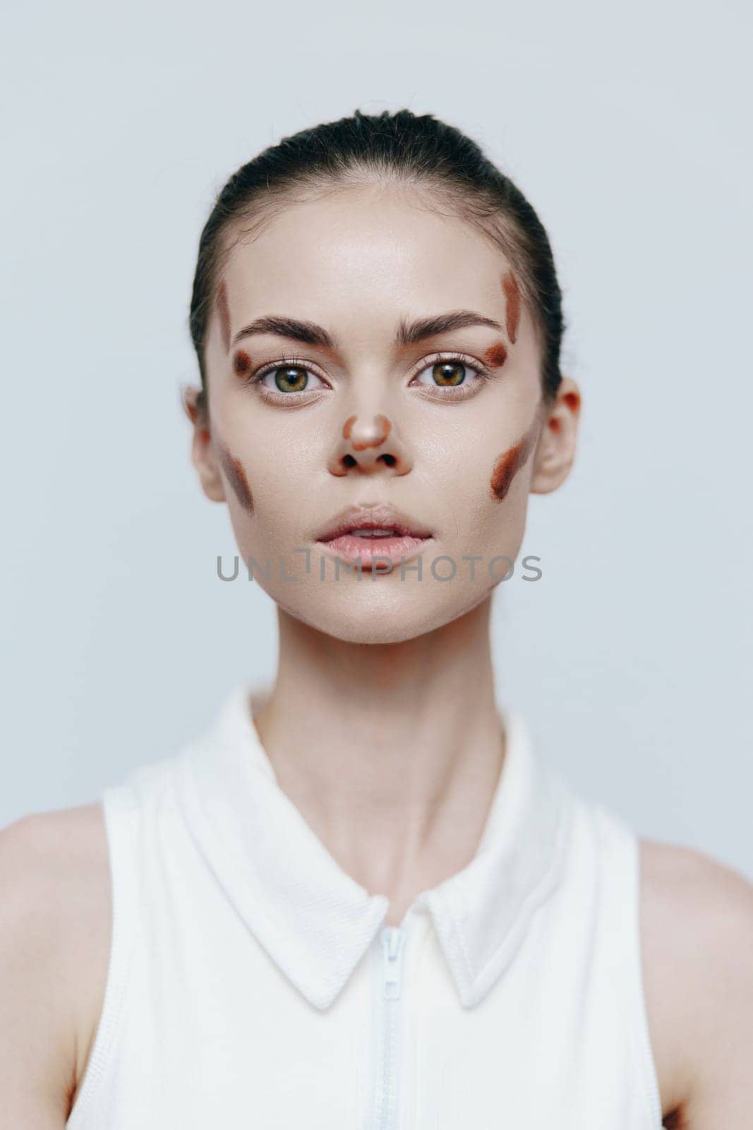 A fashionable young woman features creative face makeup, conveying a bold statement against a minimalist backdrop, merging art and beauty for a fresh seasonal look.