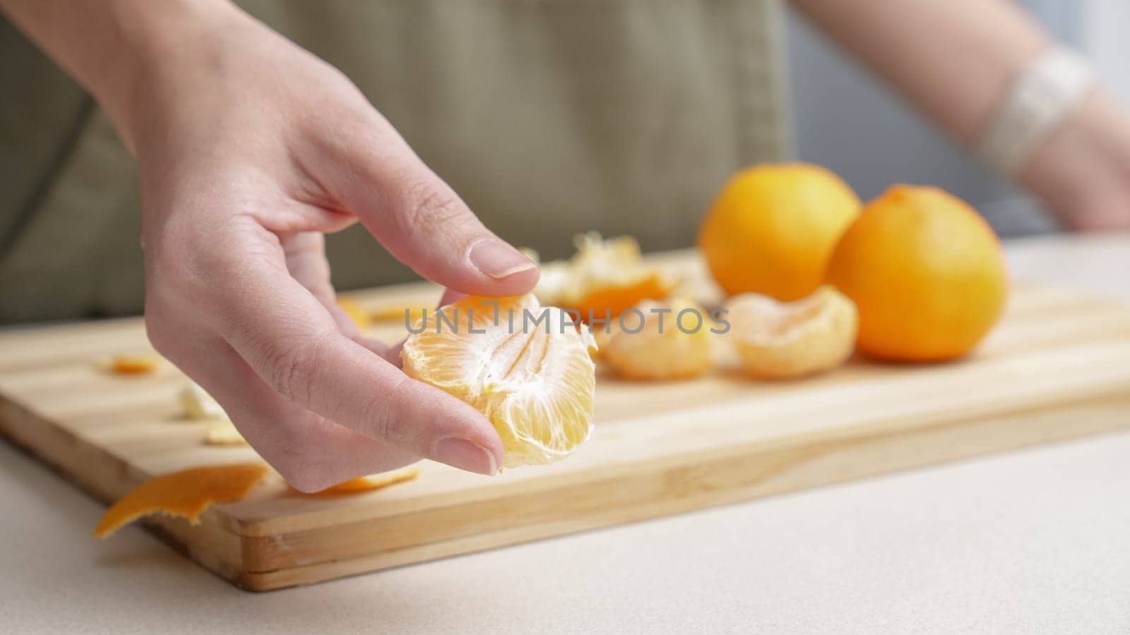 Hands peeling of orange tangerines on the cutting board on table, lots of juicy fresh fruits for cooking on Christmas.