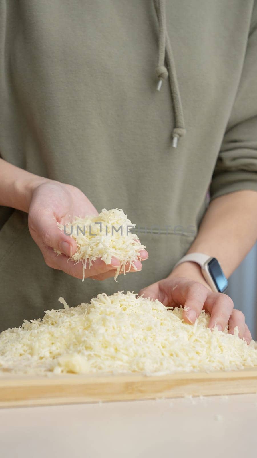 Grated cheese falls out of the cook's hand. Grated cheese for pizza