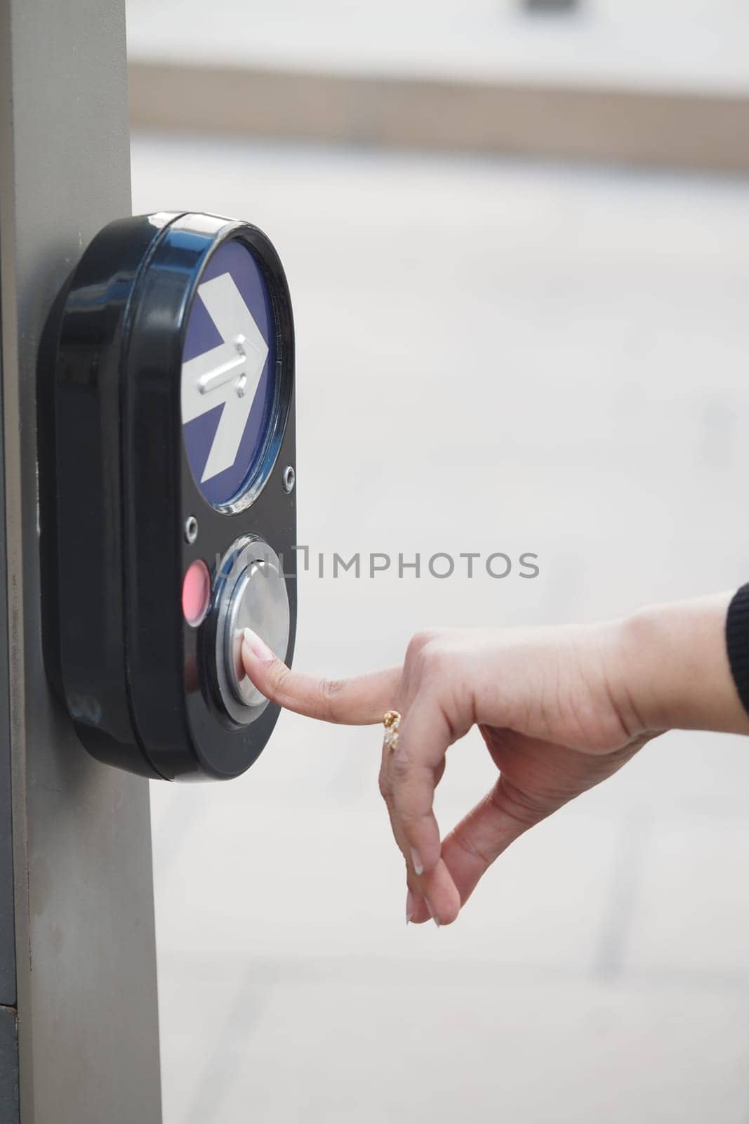 A person is pressing a button to activate a pedestrian crossing signal.