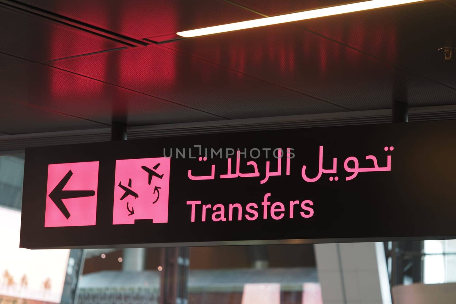 Directional sign for transfers at a busy international airport terminal.