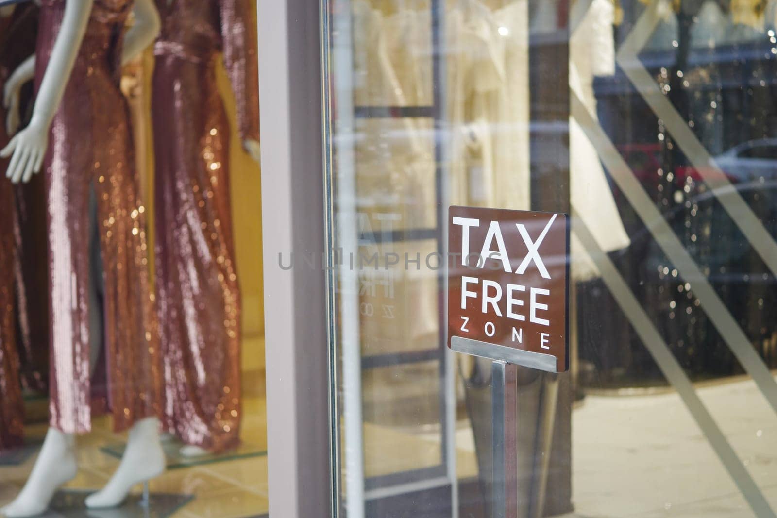 Storefront showcases elegant dresses and tax free sign.