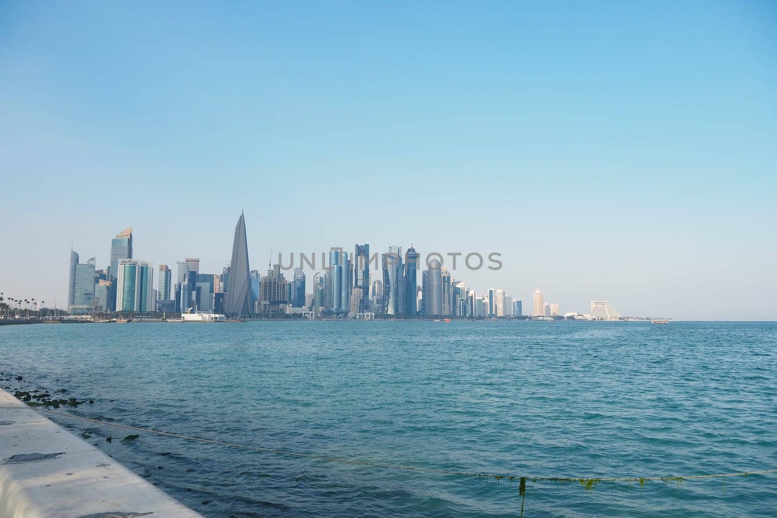 Skyscrapers line the waterfront under a clear blue sky, creating a serene view.