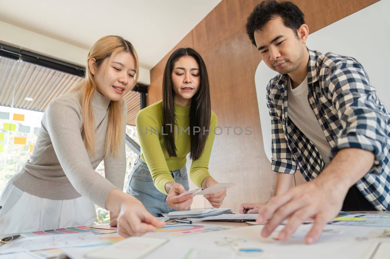 A diverse group of professionals engaged in a discussion about design ideas while collaborating around a table in a modern office environment.