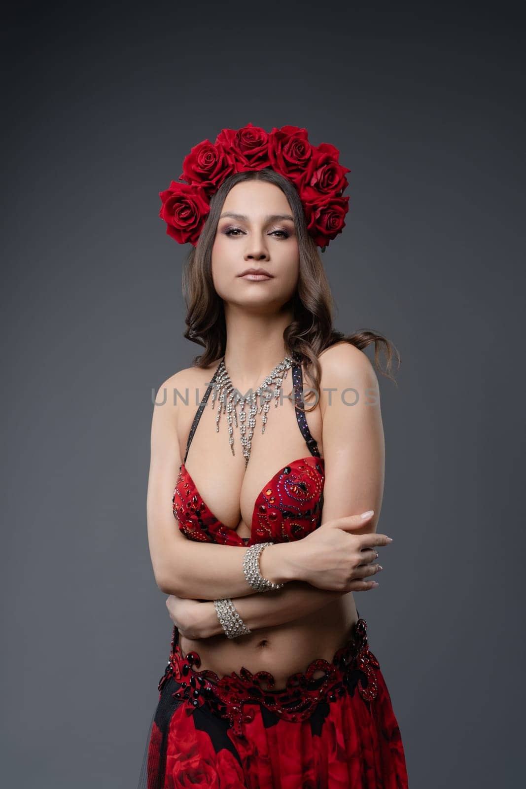 Belly dancer showcases her artistry with an elegant outfit and a floral crown in a professional studio.